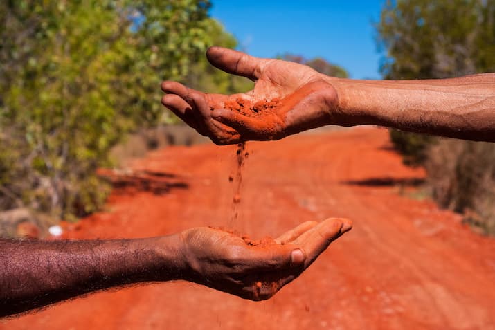 Hands passing outback sand
