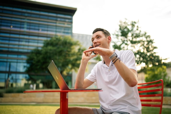 Person using laptop and mobile phone outside