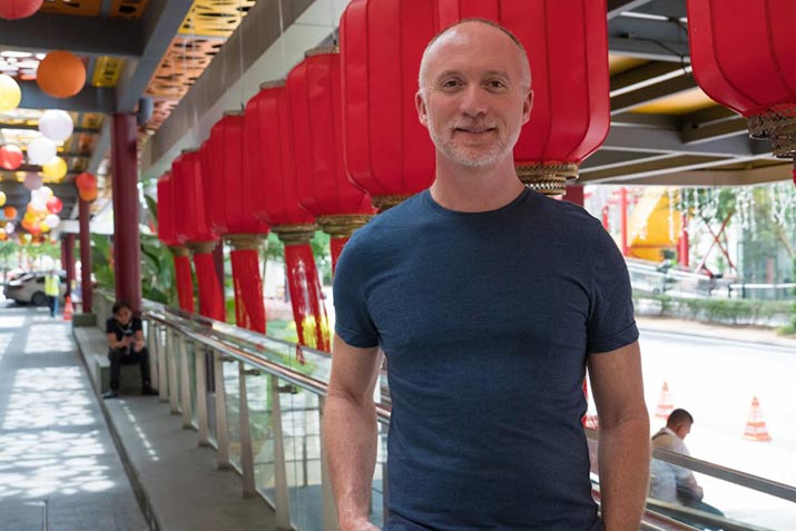 Open Universities Australia student David, standing outdoors in front of red lanterns.