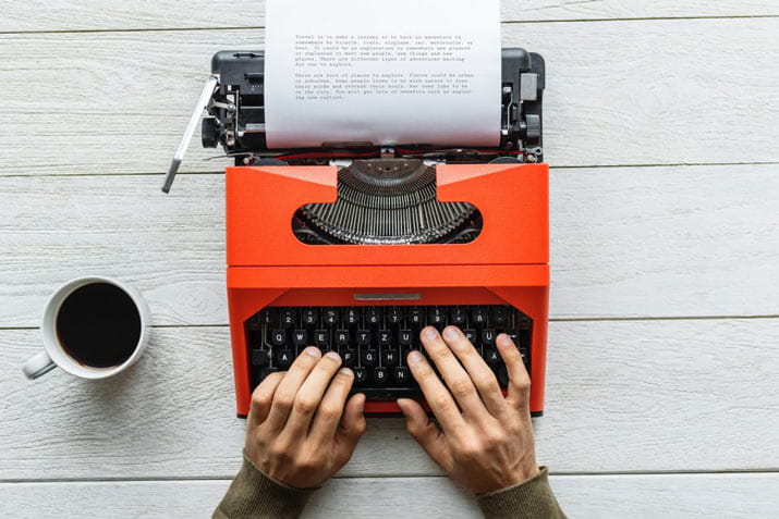 Person typing on red typewriter
