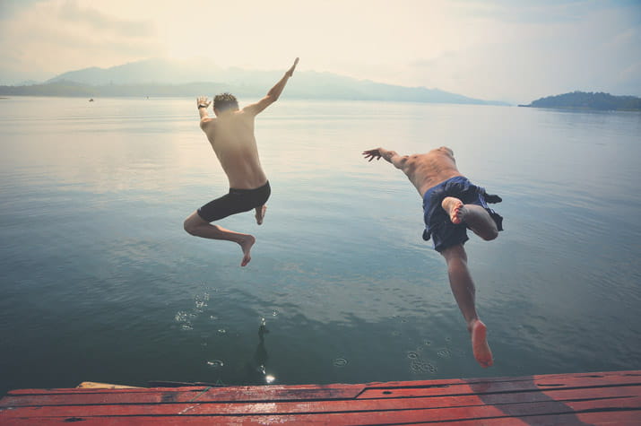 Men jumping off pier into water