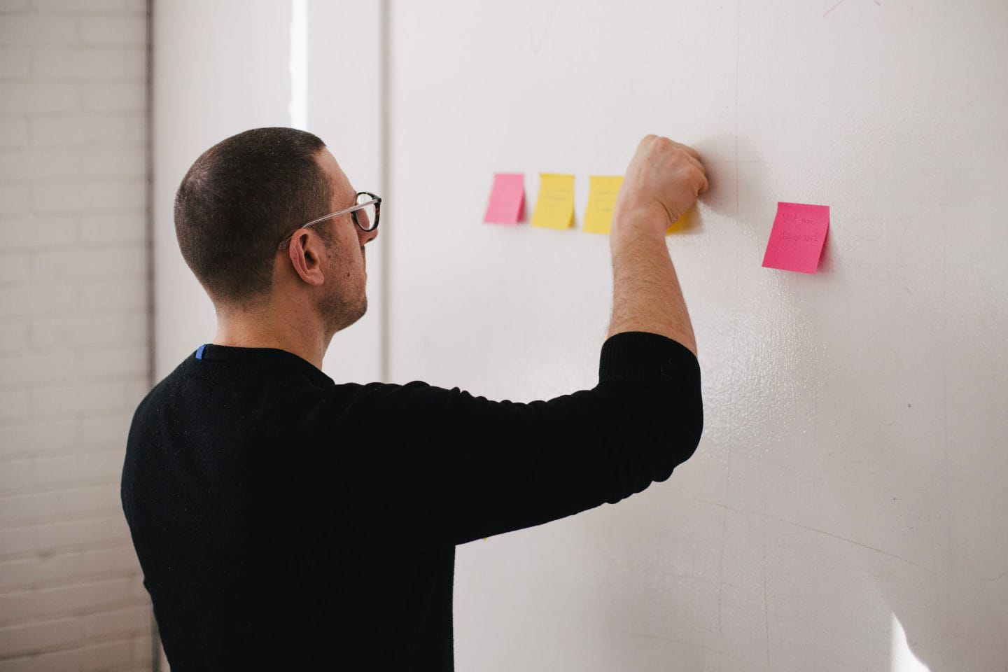man sticking post it notes to a wall