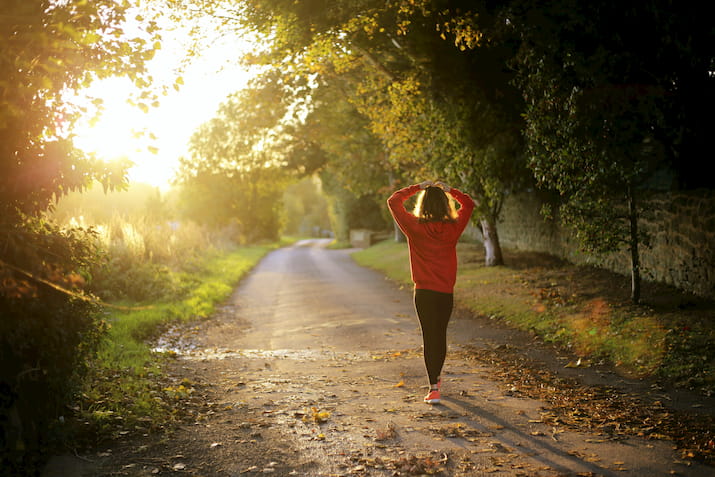 Girl walking through trees in red jumper