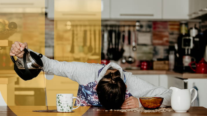 Girl with head on table pouring coffee missing the cup