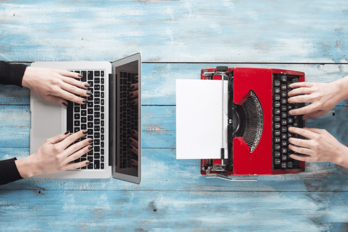 A laptop and a typewriter facing each other