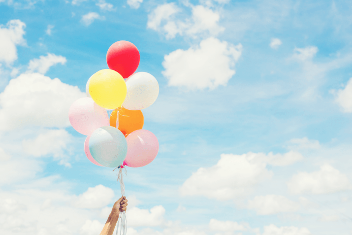 Someone holding balloons against a sky