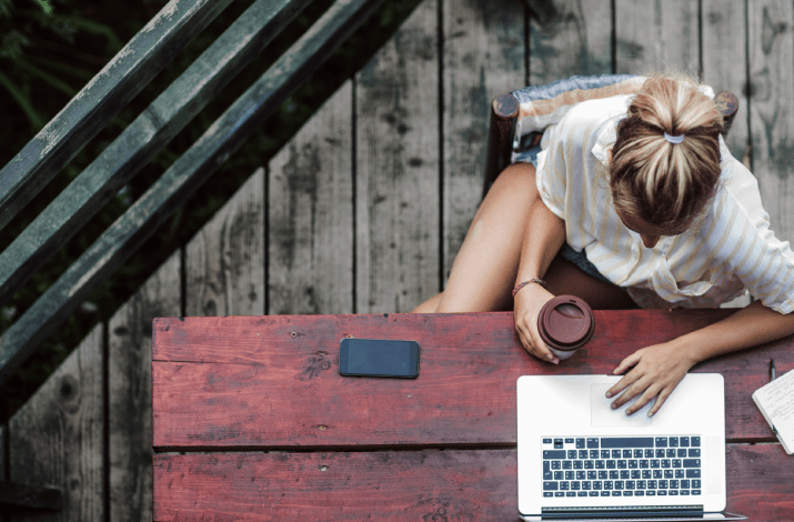 A young woman sitting at a picnic table and working on her laptop