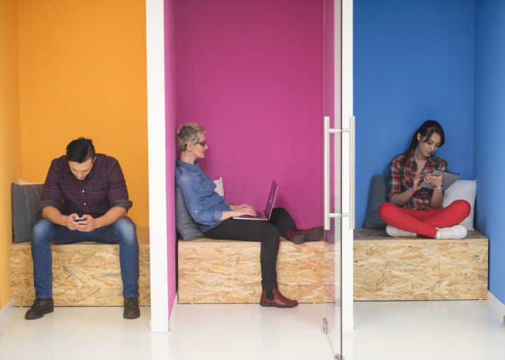 Three people working inside seperated colourful office pods