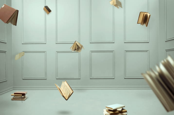 Books flying around a grey room