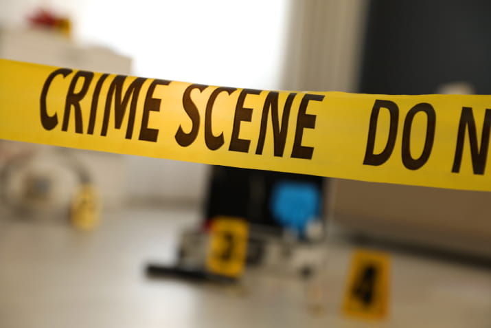 Crime scene tape over a blurred crime scene