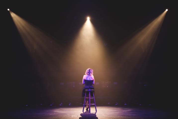 A solo performer illuminated on stage with spotlights