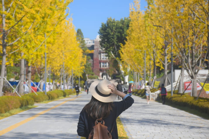 A woman in a hat walking up to a university campus