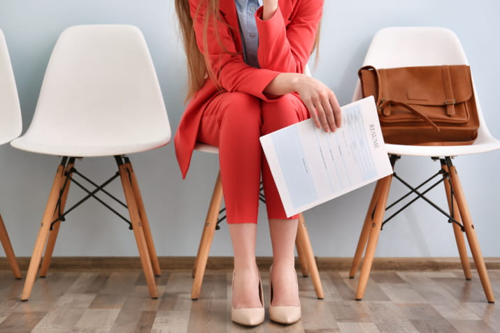 A woman in a bright orange suit waiting for a job interview