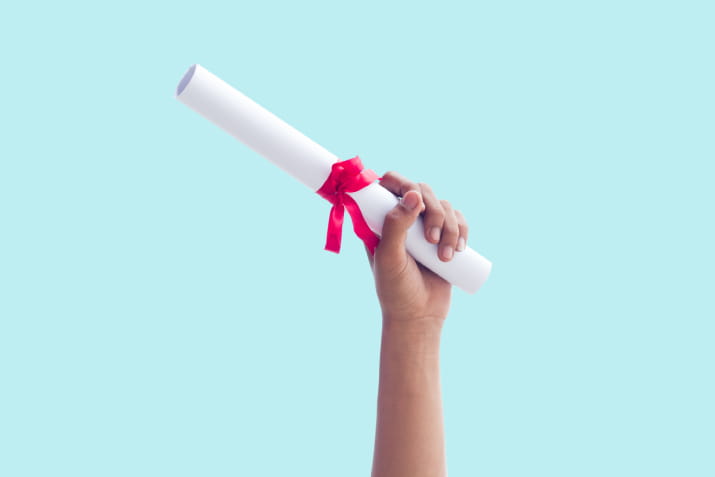 A diploma held up against a blue background