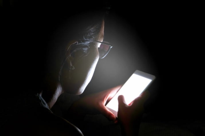 Woman in the dark looking at phone