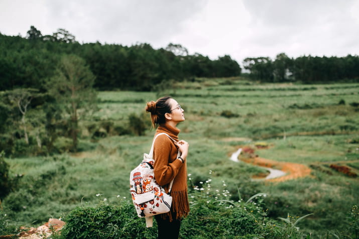 A woman wearing a backpack in a field