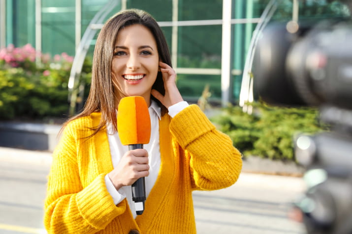 A young female journalist holding a microphone and smiling