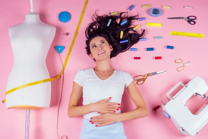 Woman laying down surrounded by sewing materials