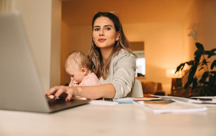 Woman holding baby working at computer