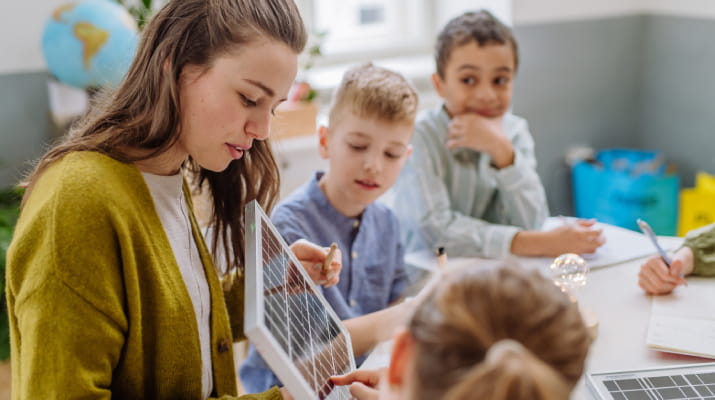 A young teacher instructing primary school students about solar energy