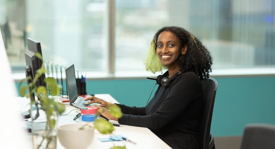 Open Universities Australia student advisor, Nabila, seated at a workstation.