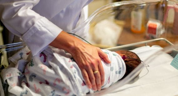 Nurse caring for a newborn baby in a hospital bassinet