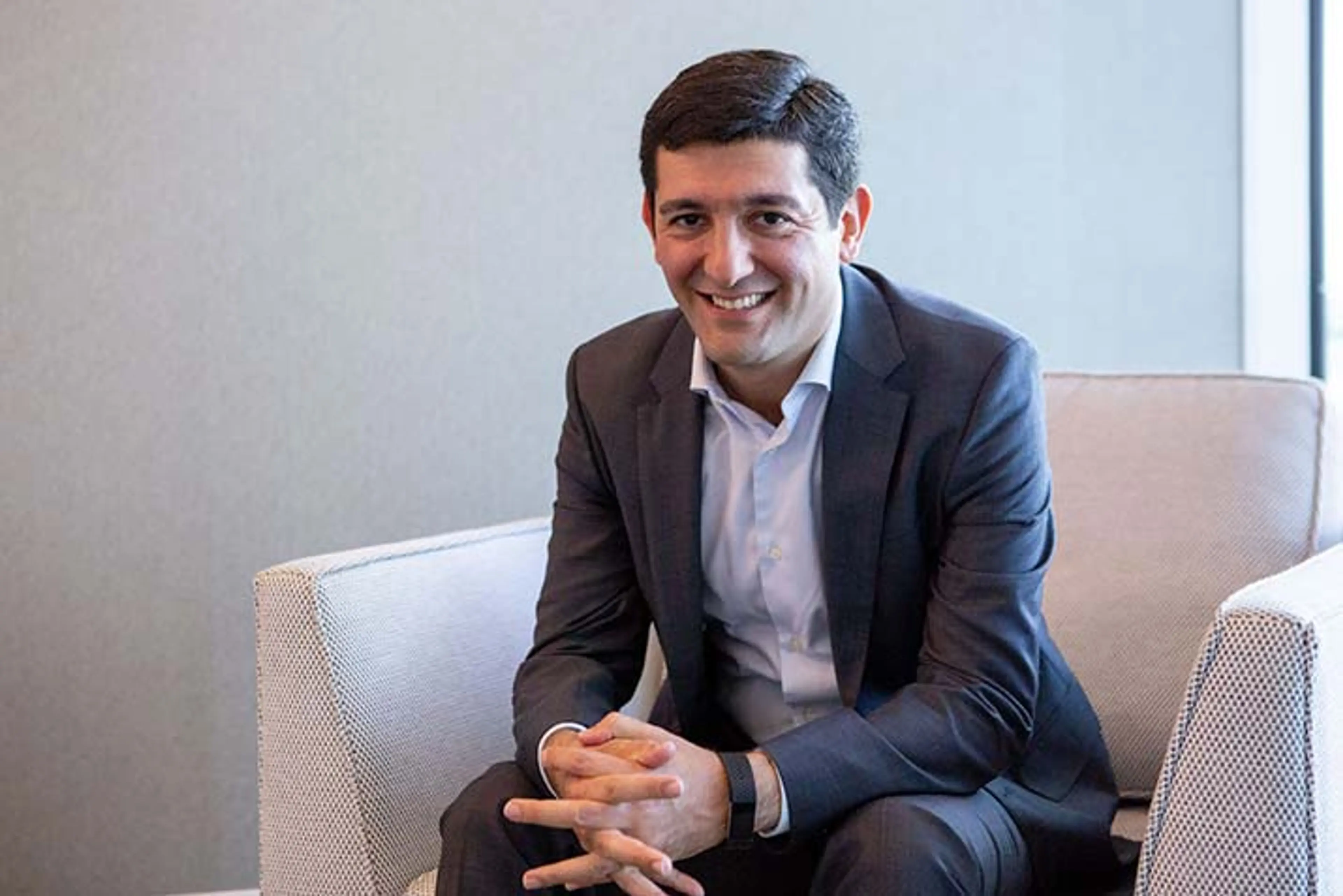 Open Universities Australia student, Behnoud, sitting in a chair, wearing a suit.