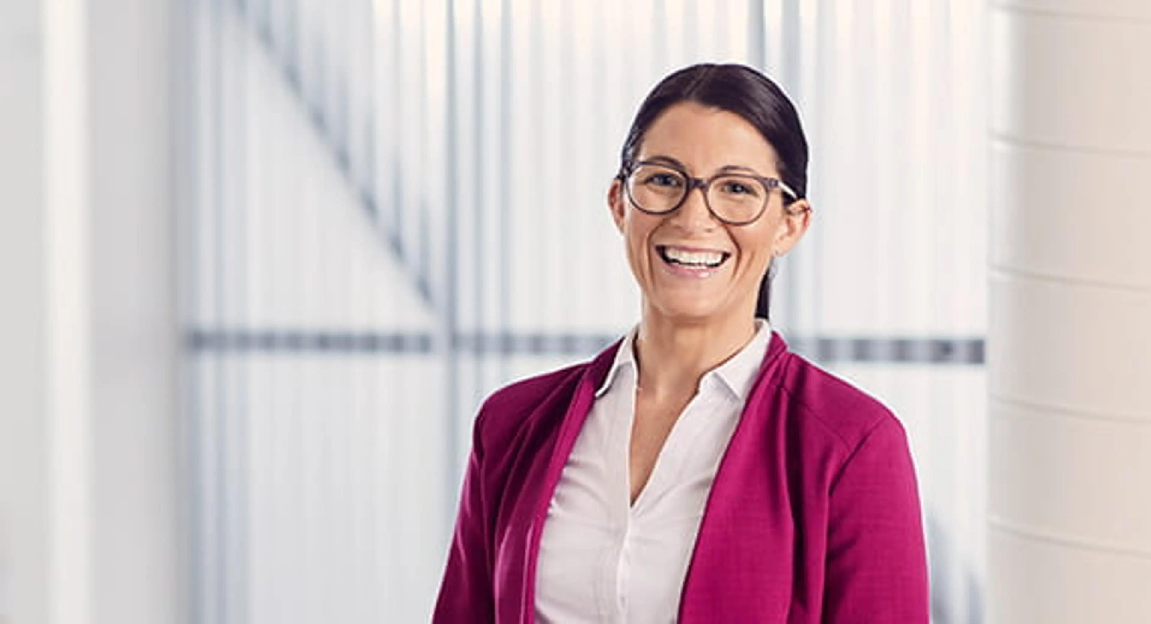 Open Universities Australia student, Melissa, wearing professional clothes in a workplace setting.