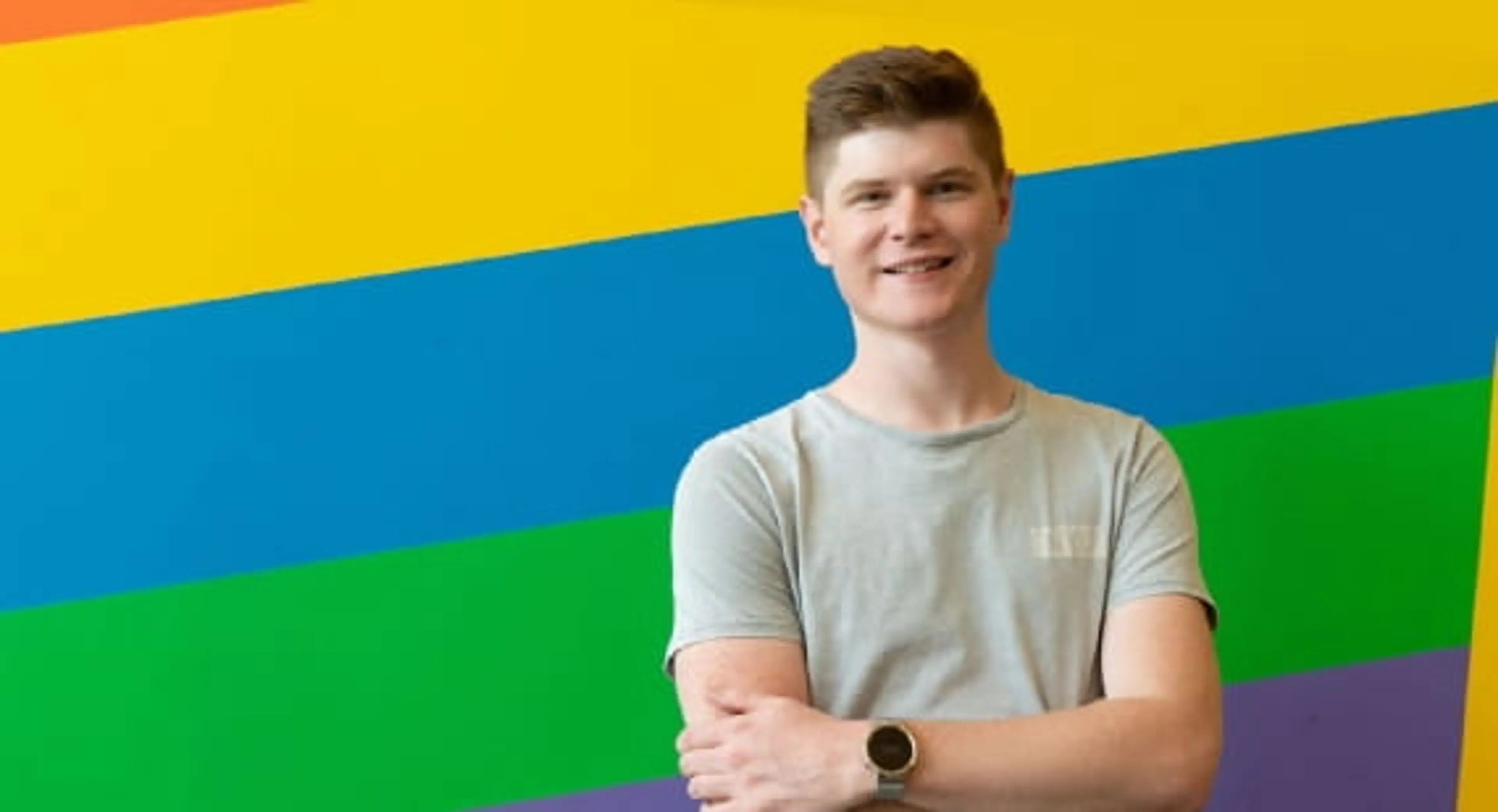 Open Universities Australia student, Ben, standing in front of a colourful wall.