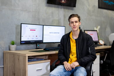 Open Universities Australia student, Darren, sitting at a workstation with a computer and two monitors.
