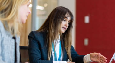 Open Universities Australia student Adriana wearing professional clothes in a workplace meeting.